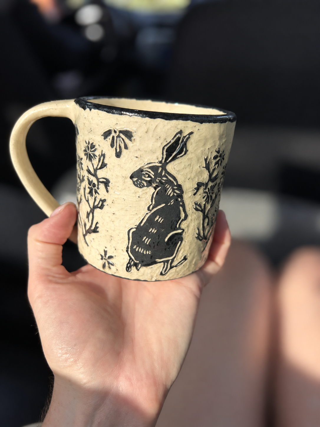 Carved rabbit and floral detail on a cream ceramic mug